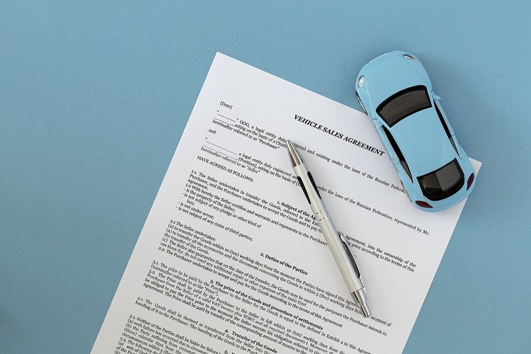 Toy car on top of paperwork with pen